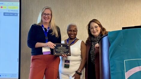 M. Nikki Freeburg receives an award from two presenters.