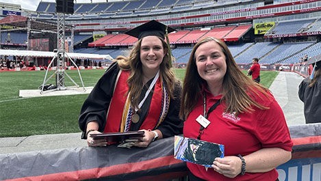 A graduate presents a donation to a BSU staff member at Gillette Stadium.