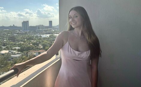 A woman stands smiling on a balcony