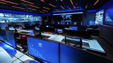 The inside of the cyber range with numerous computer monitors and a large wall-mounted display.