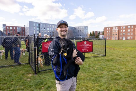 A man smiles holding a dog 