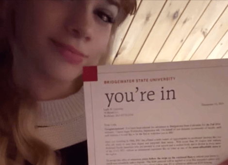 Smiling girl holds up an acceptance letter to Bridgewater State