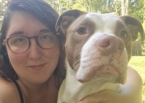 A woman wearing glasses poses with her dog 