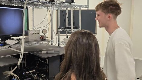 Two students work with optical equipment in a lab.