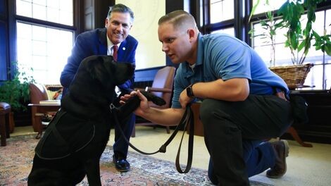 A dog shakes hands with a police officer