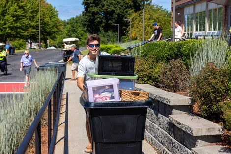 A man wearing sunglasses pushes a cart with many items in it