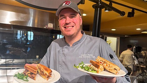 Andrew Pereira holds two plates of sandwiches.