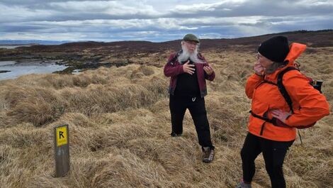 John Sexton speaks to a colleague in front of a wide Icelandic landscape.
