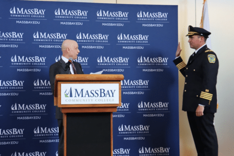 A man wearing a police uniform has his hand up and is sworn in 