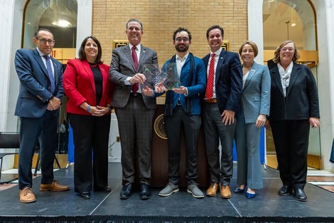 A group of people stand smiling and holding an award 