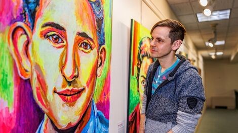 Bry Sharland looks at one of his portraits hung in a gallery.