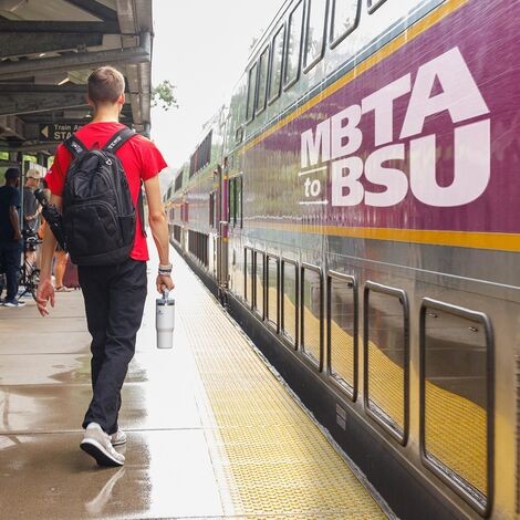 A man wearing a backpack walks towards a train 