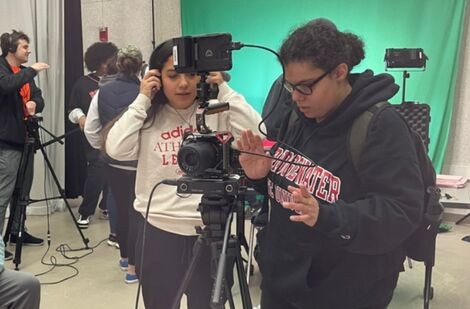 A woman looks down at a camera as she films a scene for a movie