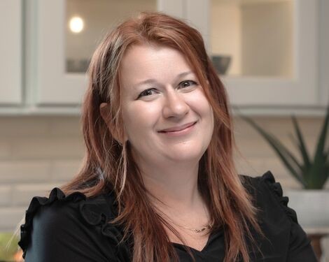 A woman with red hair smiles at the camera