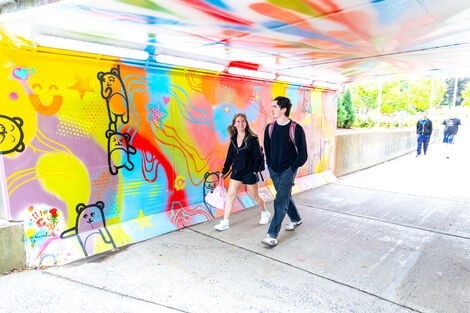 Two people walk through a colorful tunnel 