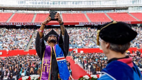 A graduate takes a selfie of the crowd from the commencement stage.