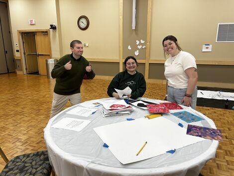 A group of people are at a table painting and smiling