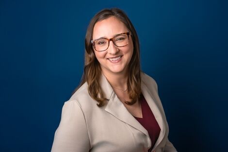A woman wearing glasses smiles at the camera 