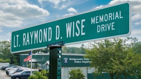 The street sign for Wise Memorial Drive with the police station in the background.