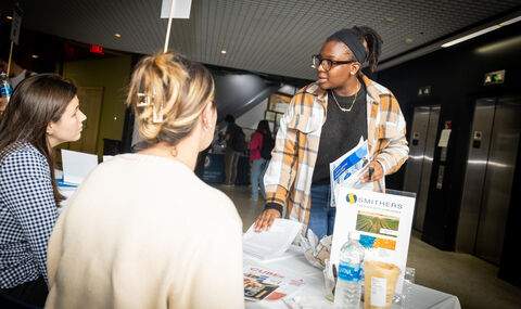 A student takes a flyer from a table at the STEM internship fair