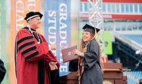 A graduate receives her diploma from President Fred Clark