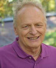 Joseph D'Adamo smiling with short wavy gray hair and wearing a purple polo shirt