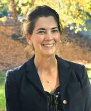 Dr. Kathleen Ferris with long dark hair pulled back wearing a black blazer over a black top