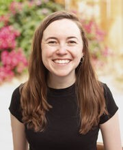 Dr. Sarah Griffes smiling with long straight red hair and wearing a short sleeved black top