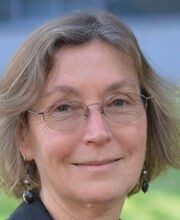 headshot photo of Dr. Karen Hamilton smiling with medium length light brown hair with gray in it and wearing thin wire rimmed glasses