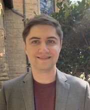 Dr. Ryan Hannagan smiling with short brown hair and wearing a grey blazer over a maroon shirt