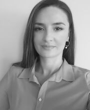 a black and white photo of Dr. Albulene Kastrati. She has long straight dark brown hair and is wearing a button up collared blouse