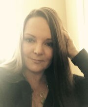 Jodie Drapal Kluver with long straight brown hair wearing a dark colored long sleeve zipper neck top