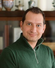 Dr. Seth Meyer smiling with short brown hair and wearing a dark green pullover with zipper neckline