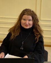 Dr. Alina Poklad smiling with long reddish brown hair and wearing a long sleeve black turtleneck sweater