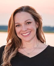 Wendy Rockne smiling with long brown hair and wearing a black v-neck top