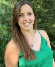 Meghan Stanton smiling with long straight brown hair and wearing a spaghetti strap green top with a v-neck