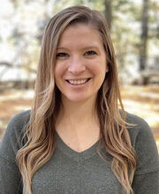 Niko Wilson smiling with long straight dirty blonde hair and wearing a green long sleeve v-neck top