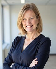 Dr. Melissa Winchell smiling with medium length dirty blonde hair and wearing a navy blue top