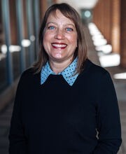 Dr. Jennifer Winters smiling with medium length brown hair and wearing a light blue polka dot collared top under a navy blue sweater
