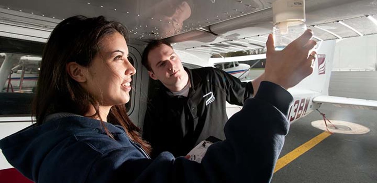 A flight instructor works with an aviation student outside the airplane A flight instructor works with an aviation student outside the airplane