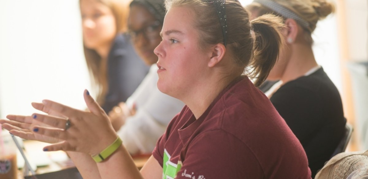 Student in classroom asking a question Student in classroom asking a question