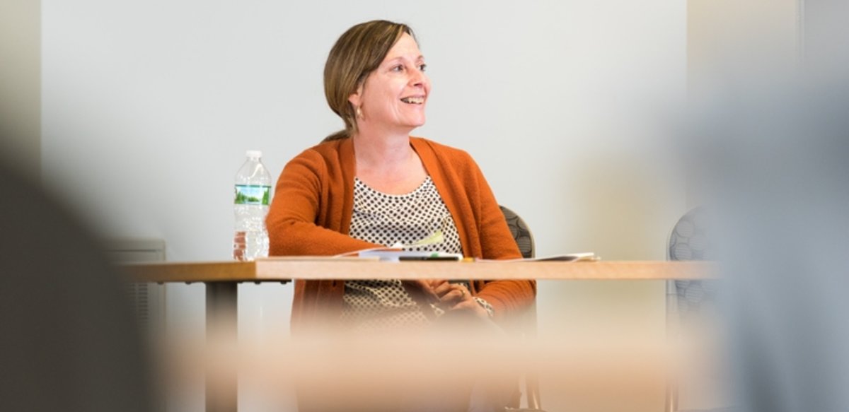 A professor sitting in class and smiling A professor sitting in class and smiling