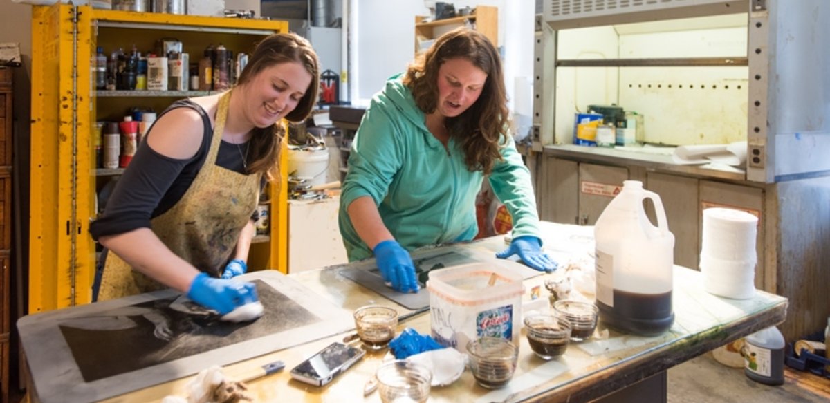 Two students working with inks at a table. Two students working with inks at a table.
