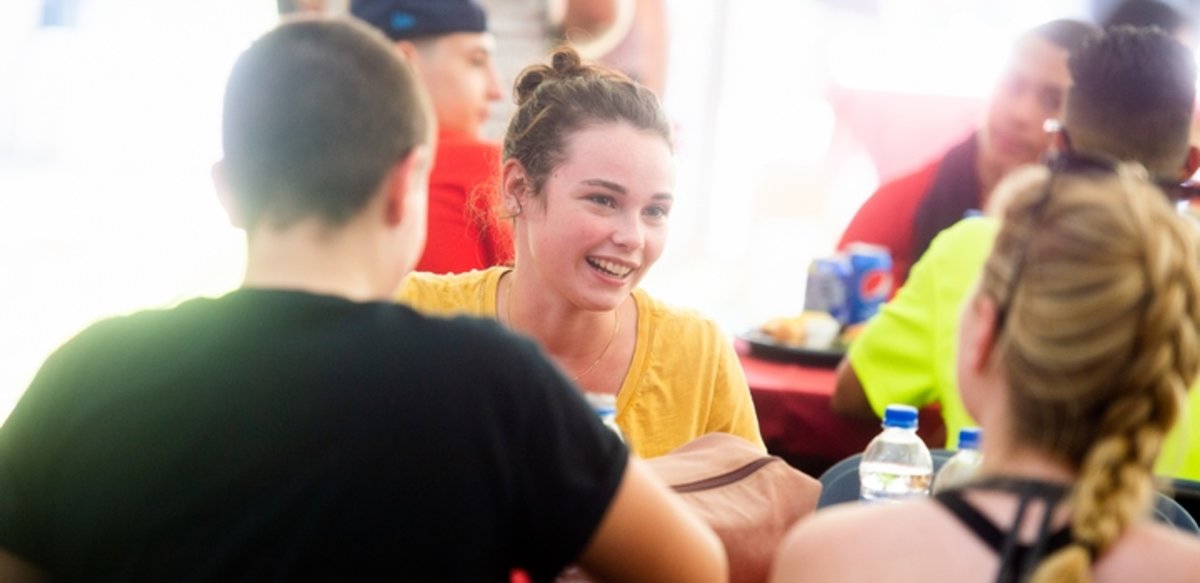 honors student sitting at a table with friends and smiling honors student sitting at a table with friends and smiling
