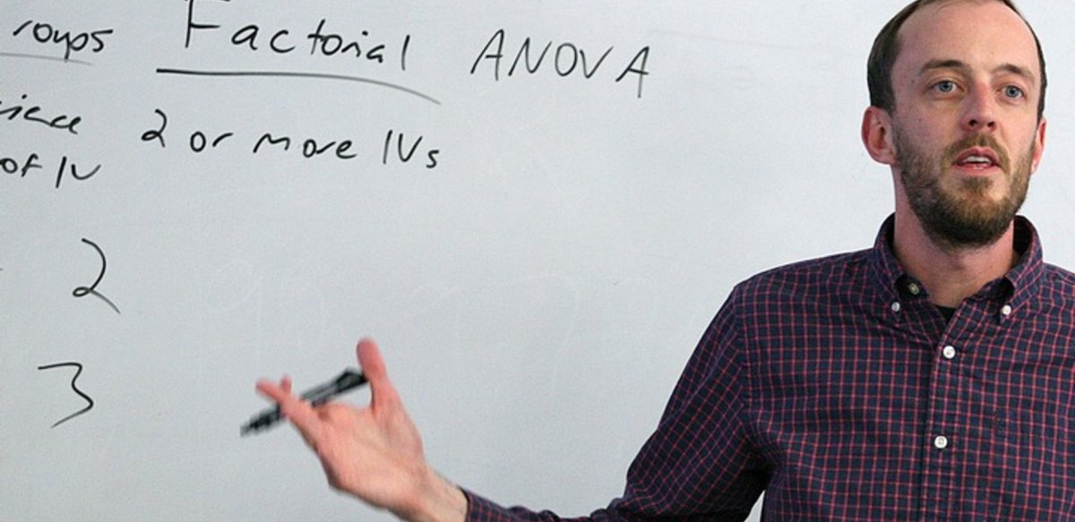 A professor speaking to a class in front of a white board A professor speaking to a class in front of a white board