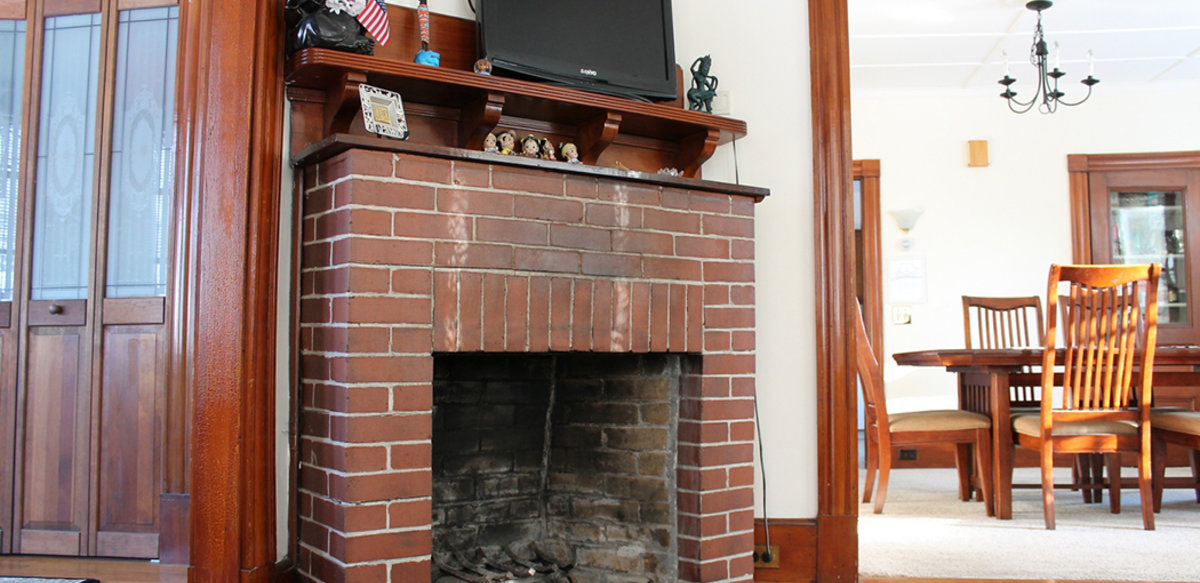 Fireplace in Scholar House living room with tv on top and dining room in background