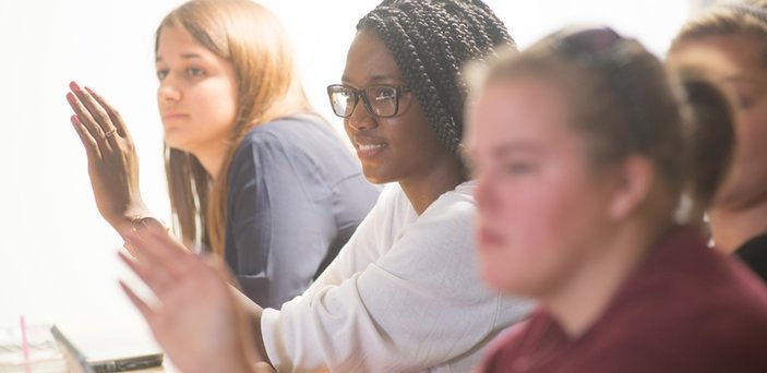 students raising their hands in class