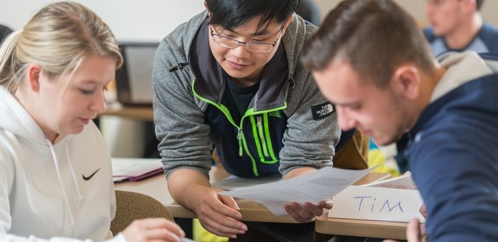 Three students doing group work in class