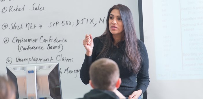 Professor Madhavi Venkatesan teaching class in front of a white board and projection screen