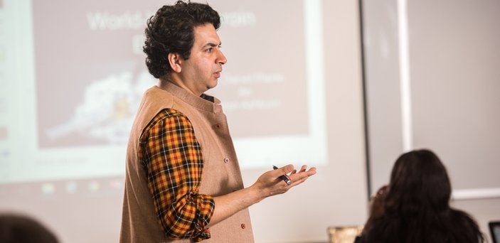 Professor speaking to class in front of projection screen